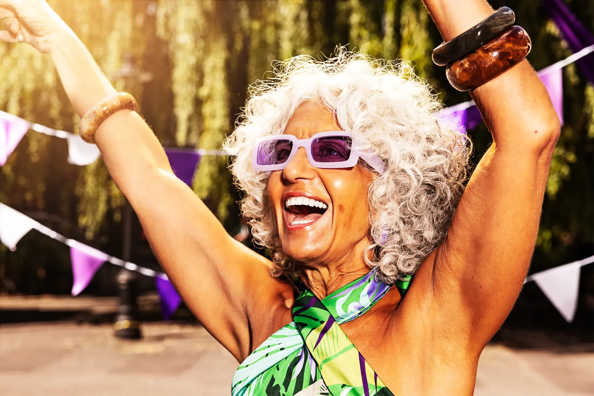 Smiling woman in sunglasses celebrating outdoors