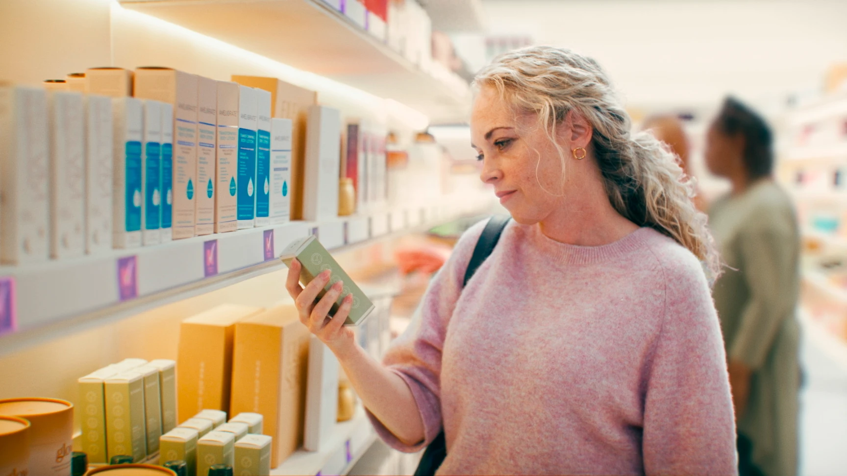 Woman checking her phone while shopping in a store aisle